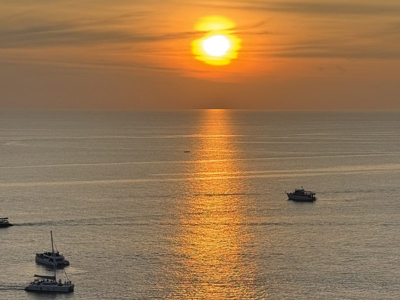 The sun setting over the sea and boats near Promthep Cape