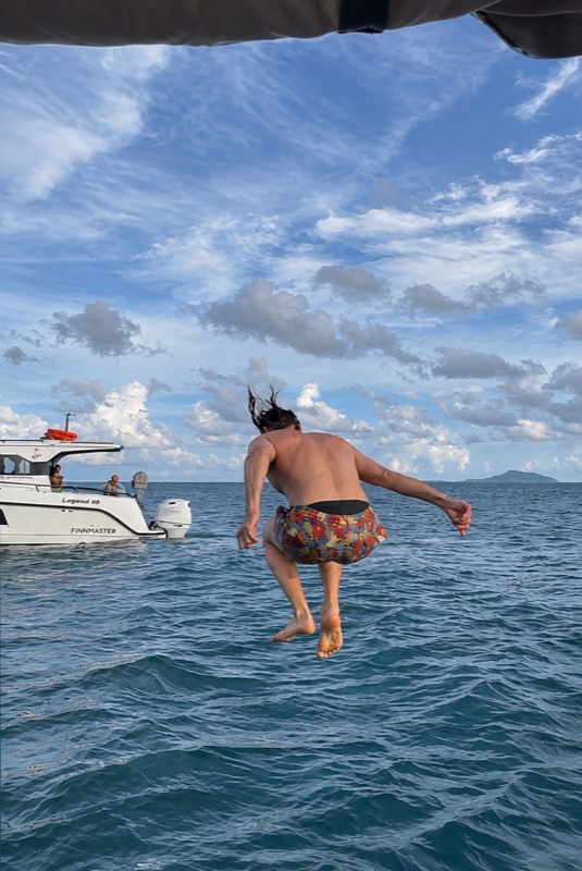 A guest jumping into the sea beside a boat
