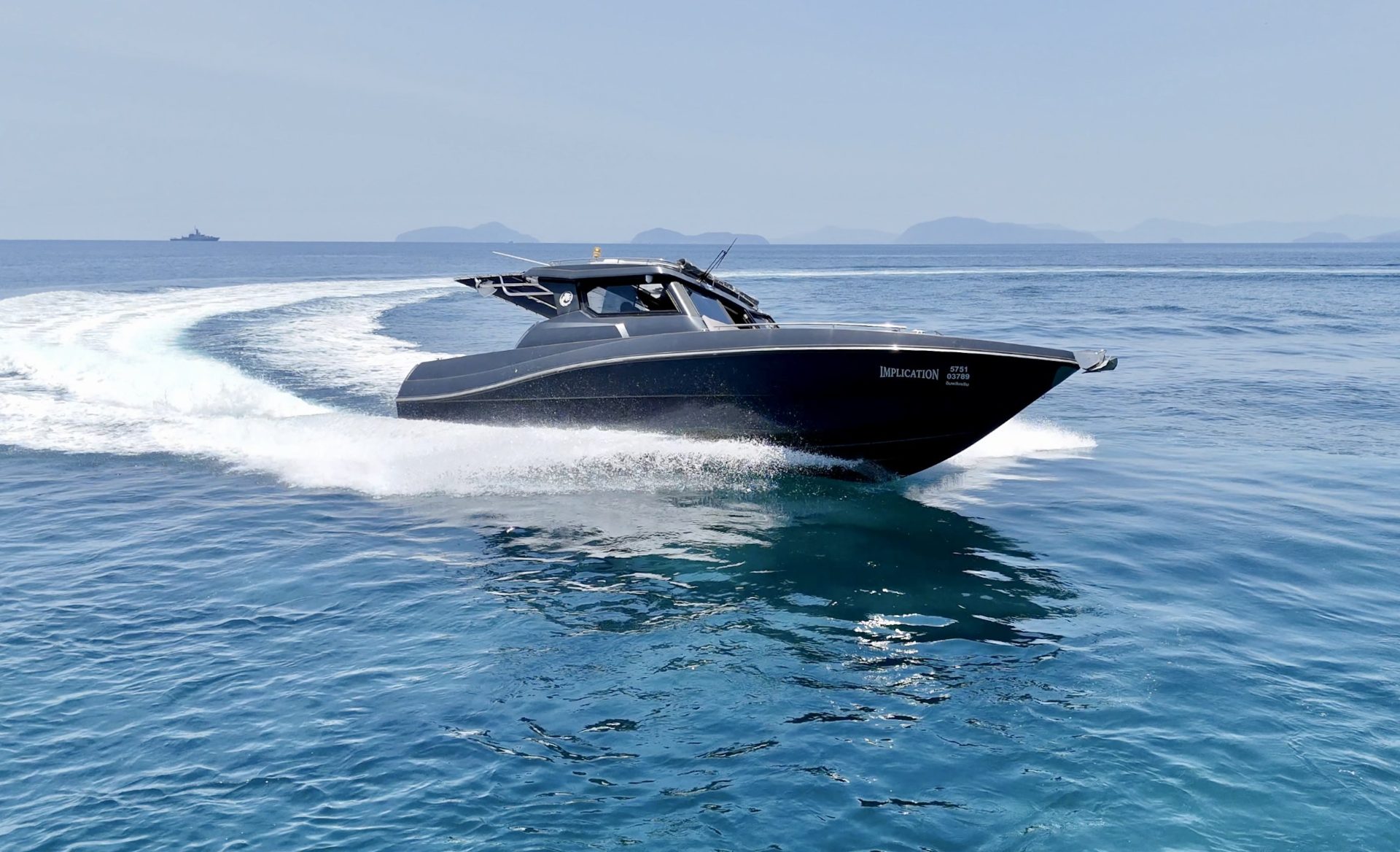Silvercraft 36HT at speed with a big wake and islands on the horizon, full hull visible