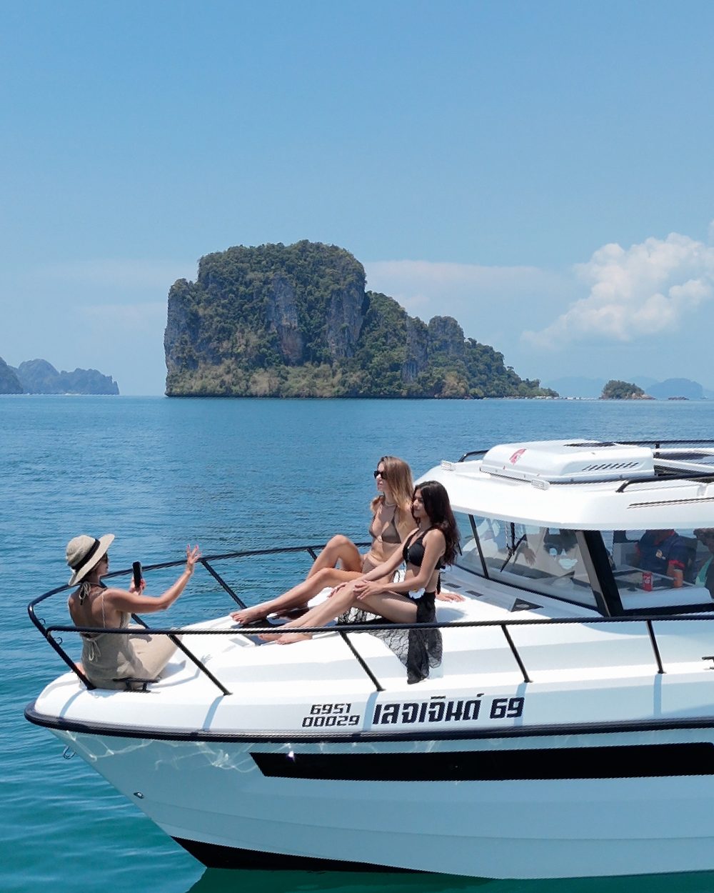 Friends relaxing on the bow near a limestone island