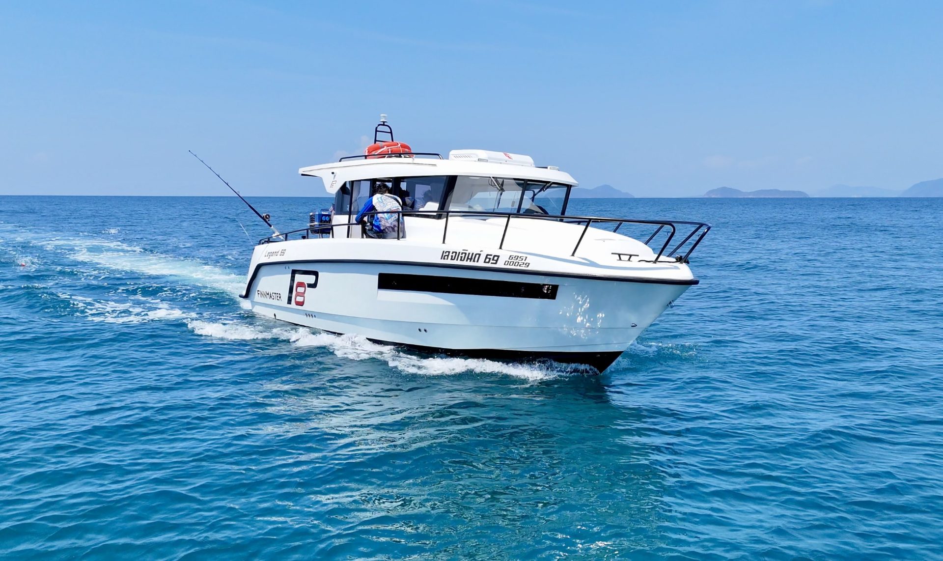 Finnmaster Pilot cruising on turquoise water with islands on the horizon, full hull visible