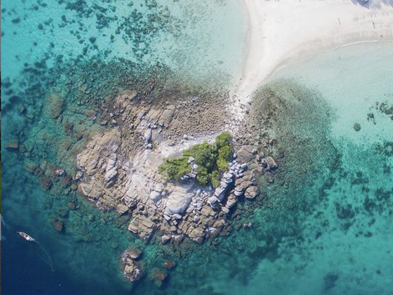 An island and its reef beside clear turquoise water