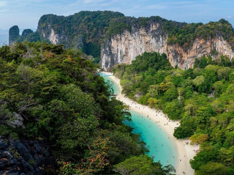 Aerial view of a curved white-sand beach tucked between forested limestone cliffs at Hong Island