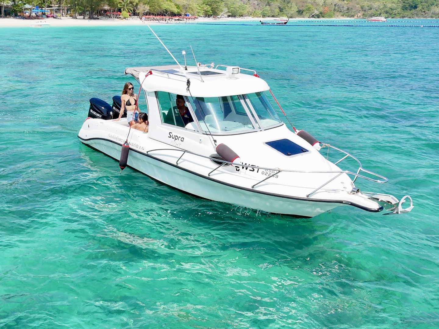 Front three-quarter view of Atomix 705HT with people aboard near a sandy beach.