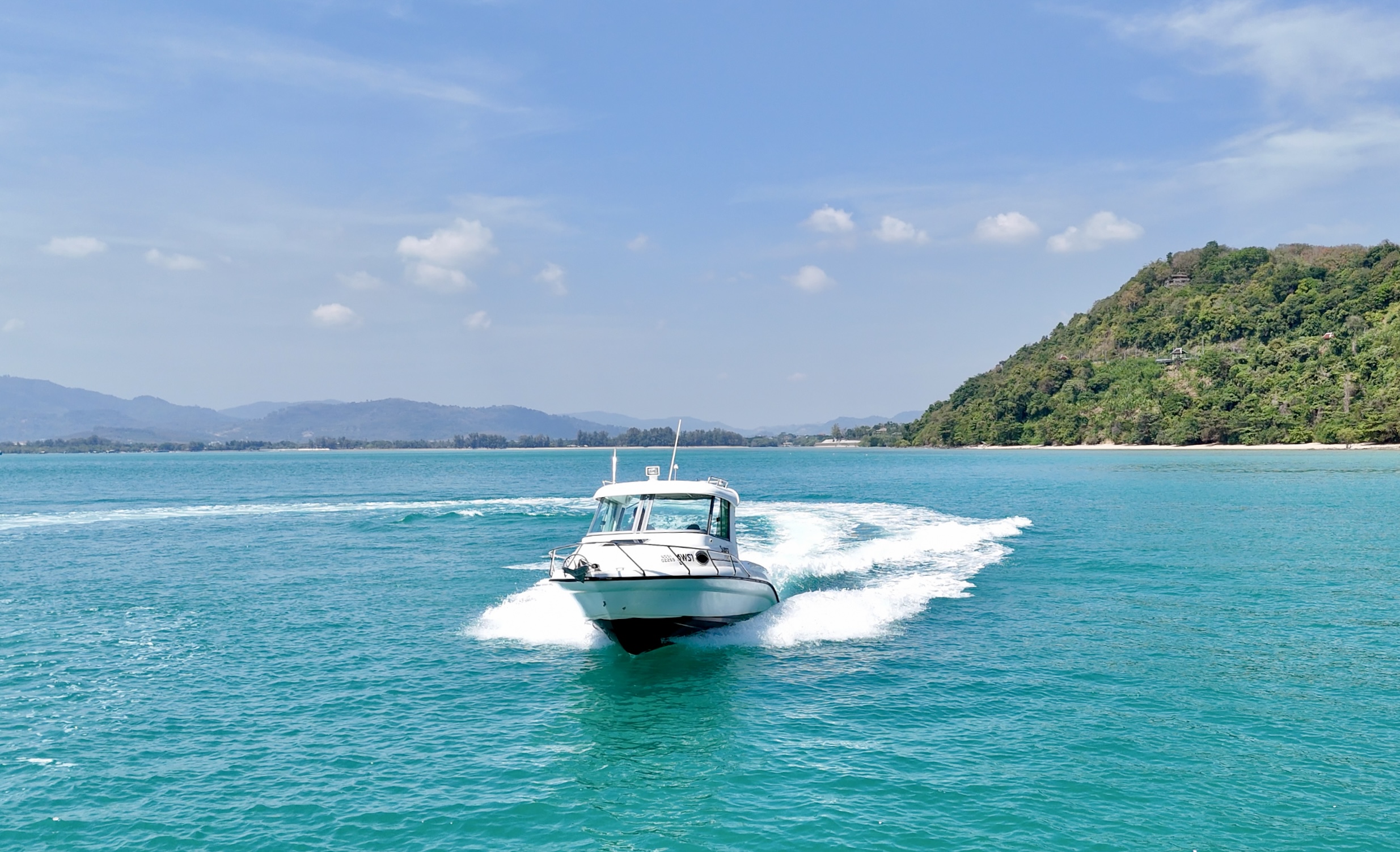 Front view of Atomix 705HT with a white wake and a green headland behind it.