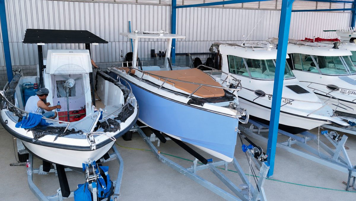 A person working on one of several boats inside the marine workshop
